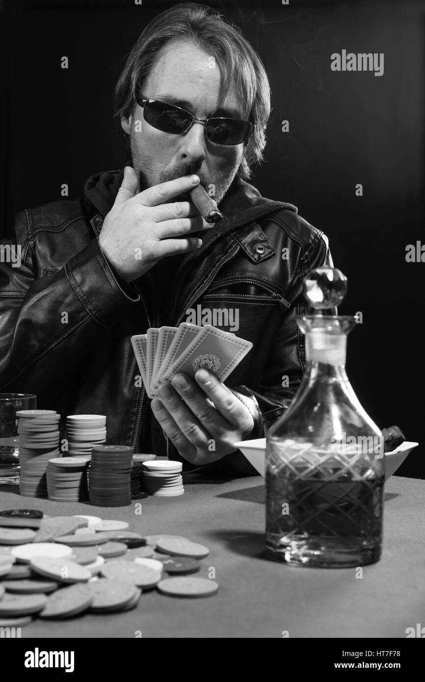 Photo d'un homme jouant au poker tout en portant des lunettes de soleil et fumer un cigare. Banque D'Images