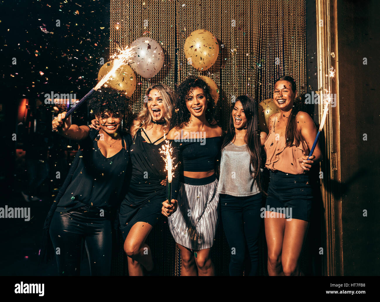 Photo de groupe de jeunes femmes célébrant le nouvel an au pub. Groupe d'amis féminins avec baguettes à la fête dans une discothèque. Banque D'Images