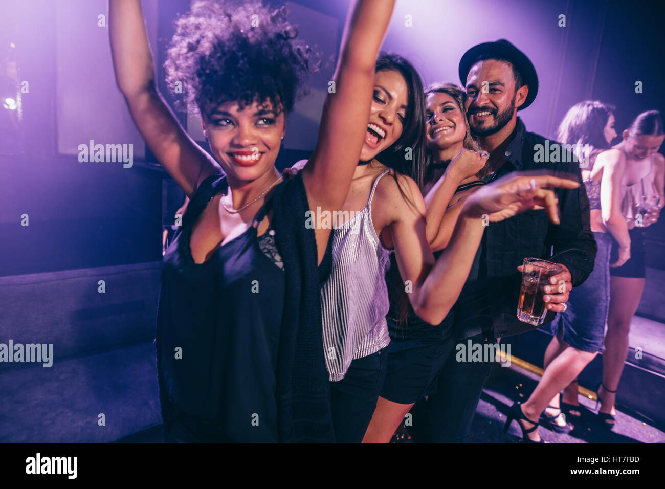 Groupe des amis danser en boîte de nuit. Les jeunes, hommes et femmes, s'amusant à disco club. Banque D'Images
