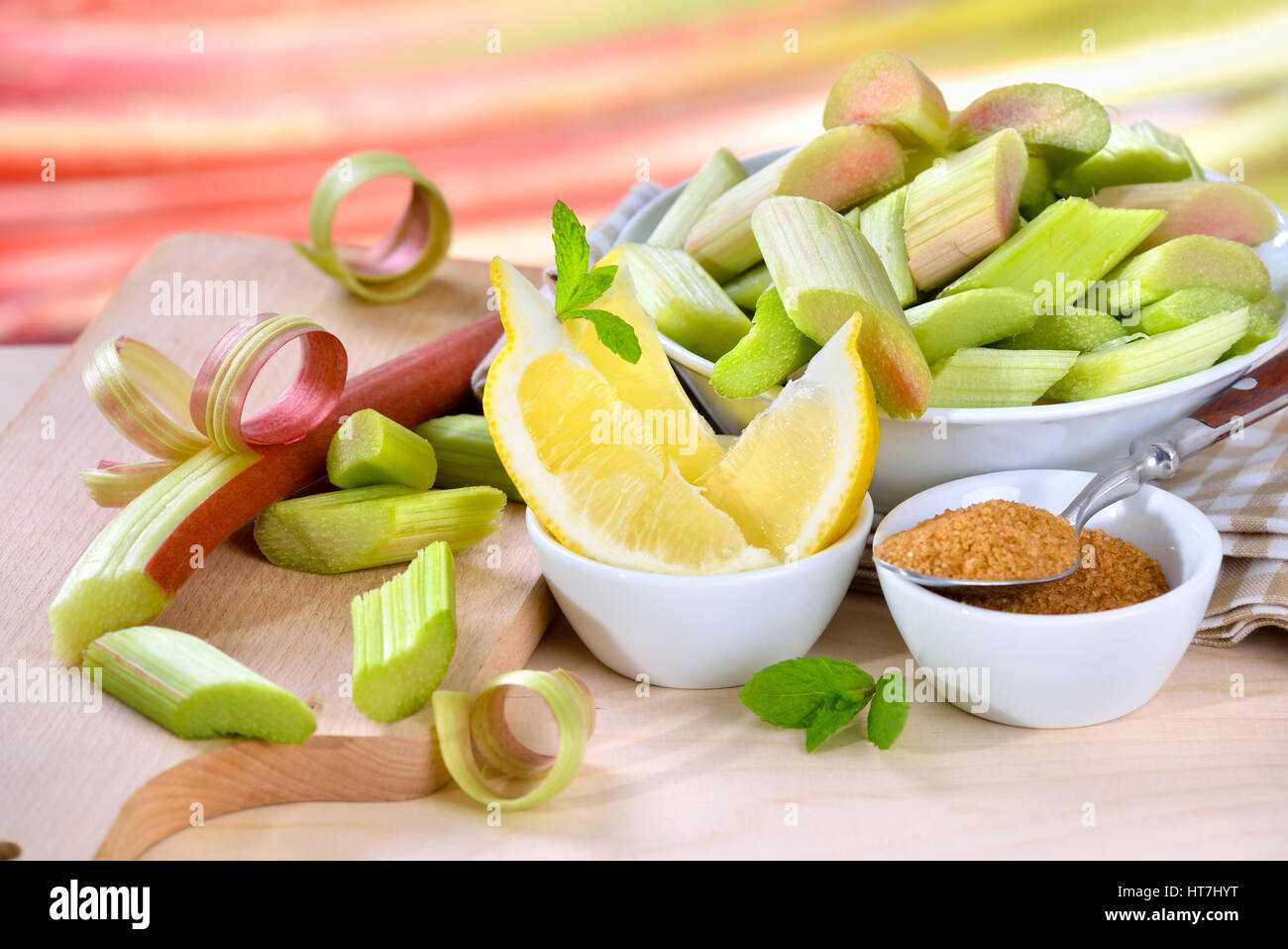 Pelé et haché matières rhubarbe compote préparés pour la cuisson avec du sucre brun et de citron, à l'arrière-plan d'autres tiges de rhubarbe dans soft focus Banque D'Images