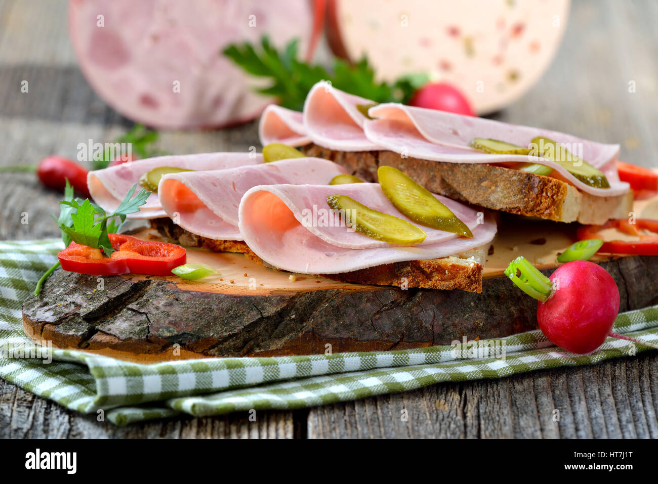 Tranches de saucisse Bavaroise sur pain de campagne, garni et servi sur une planche en bois rustique Banque D'Images