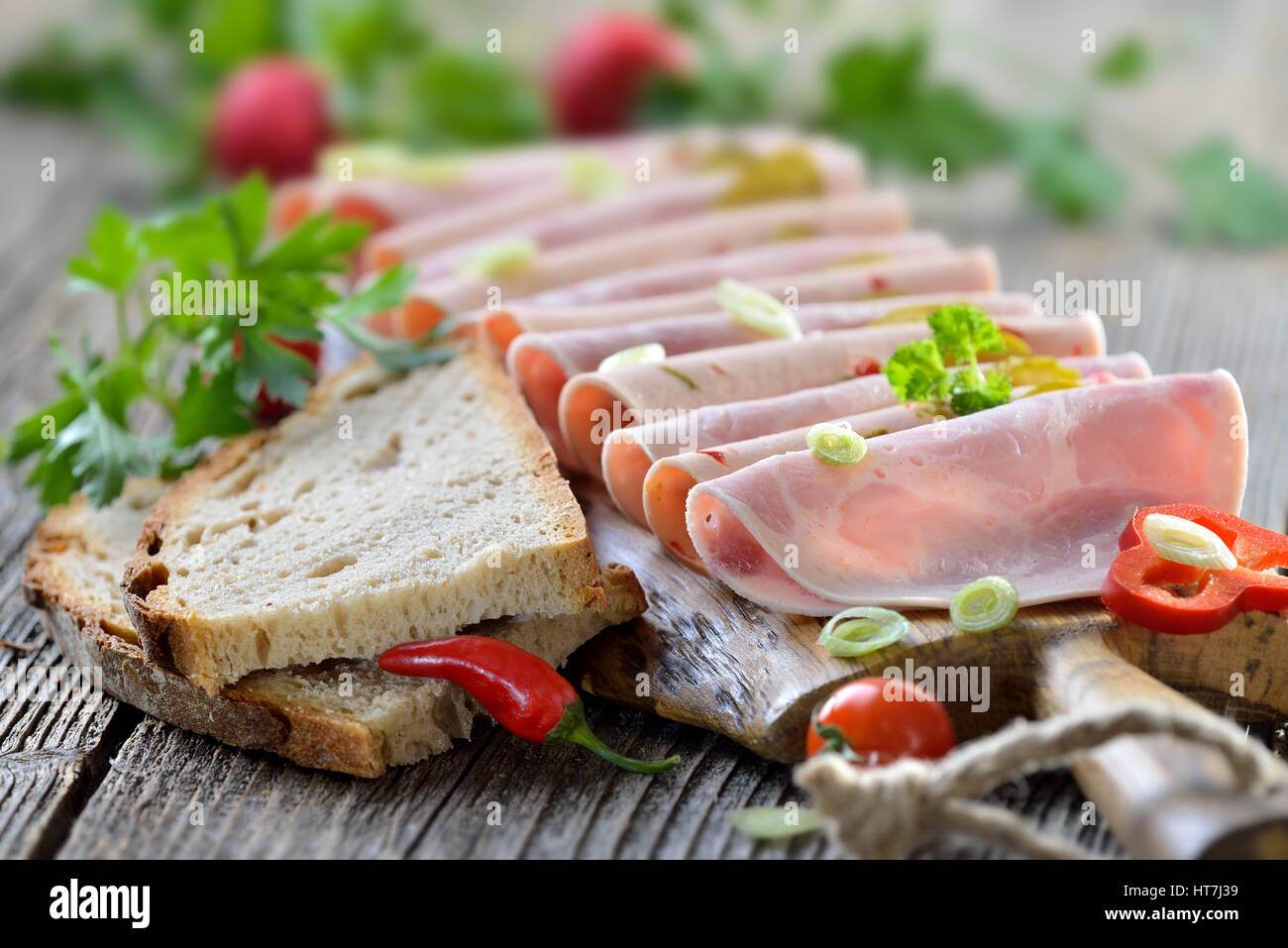 Tranches de saucisses bavaroises garni et servi avec du pain de campagne sur une planche en bois rustique Banque D'Images