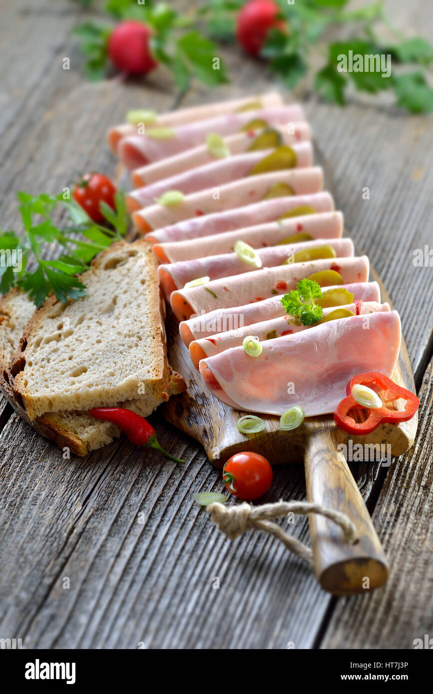 Tranches de saucisses bavaroises garni et servi avec du pain de campagne sur une planche en bois rustique Banque D'Images