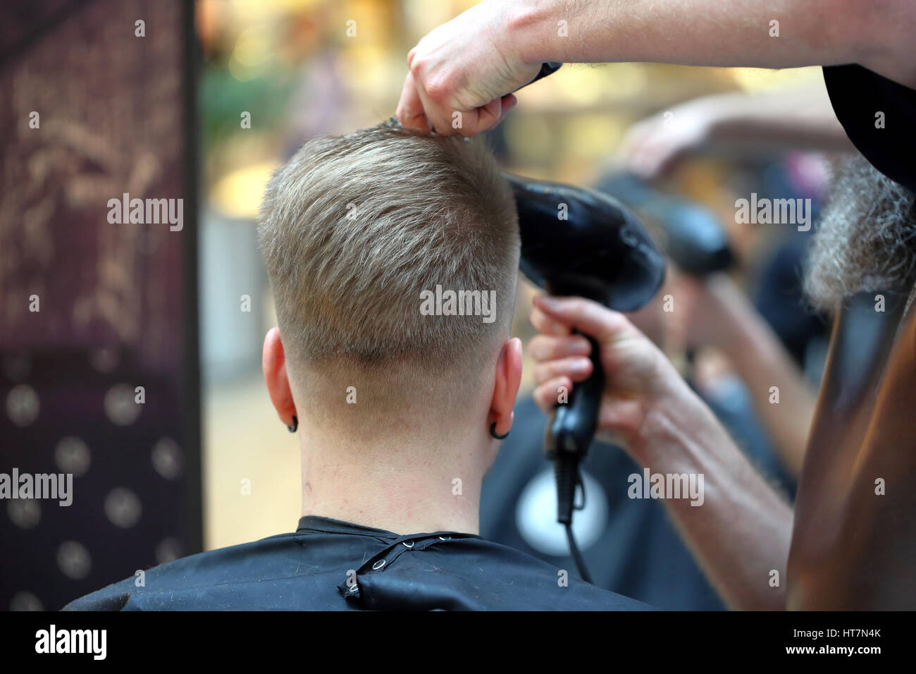 Coiffure coiffure rend avec sèche-cheveux dans un salon de barbier Banque D'Images