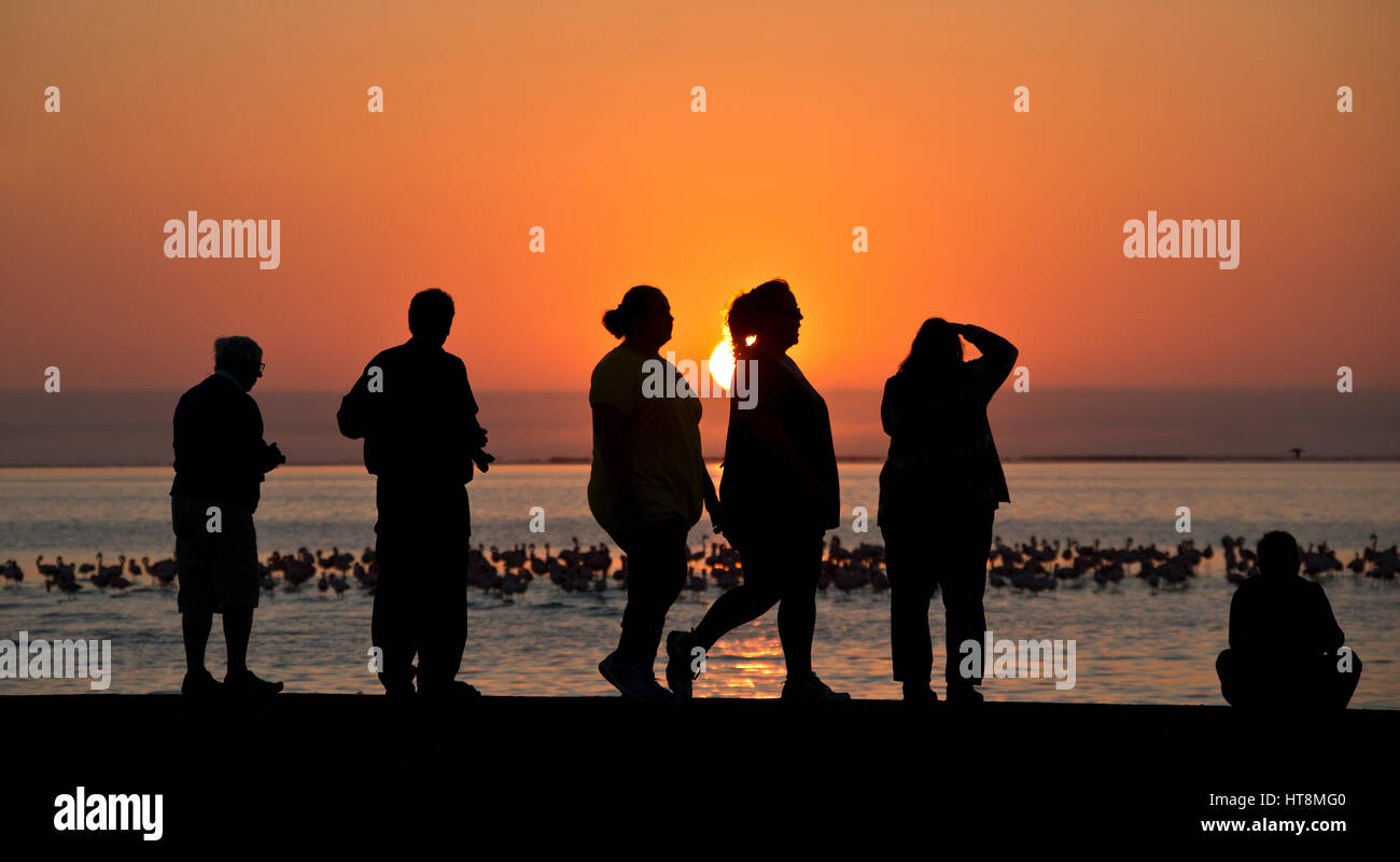 Coucher du soleil orange profond avec silouhettes de personnes au premier plan. Banque D'Images