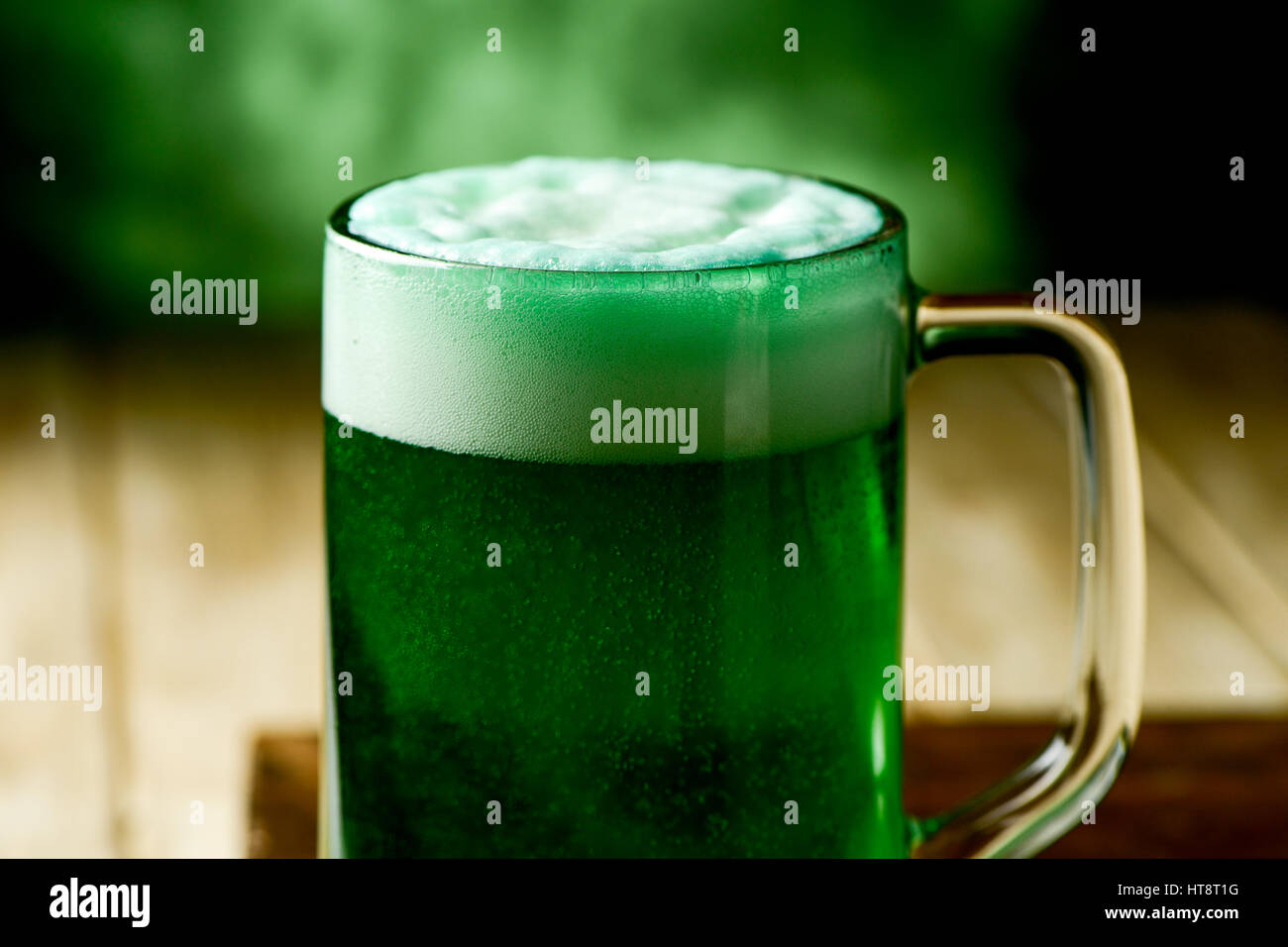 Libre d'un bocal en verre avec de la bière teint en vert sur une surface rustique en bois Banque D'Images