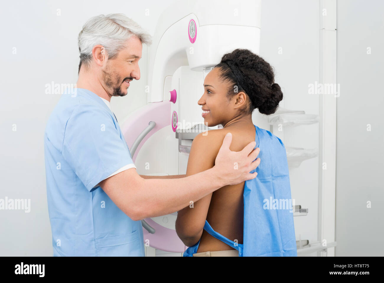 Vue latérale du male doctor looking at female patient sous mammographie examen radiologique à l'hôpital Banque D'Images