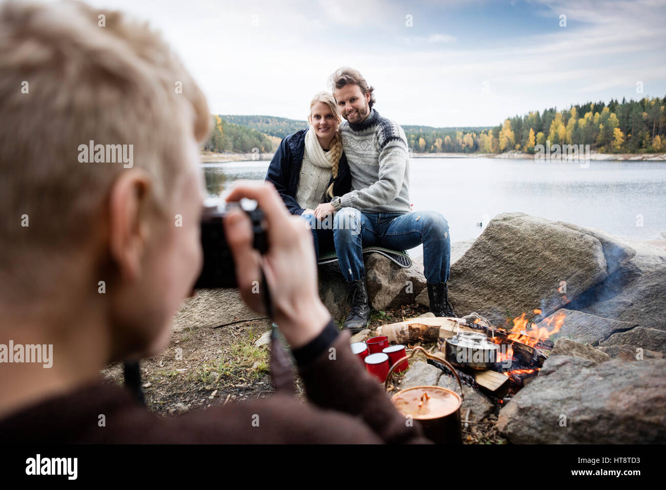 Young man photographing couple au camping au bord du lac Banque D'Images