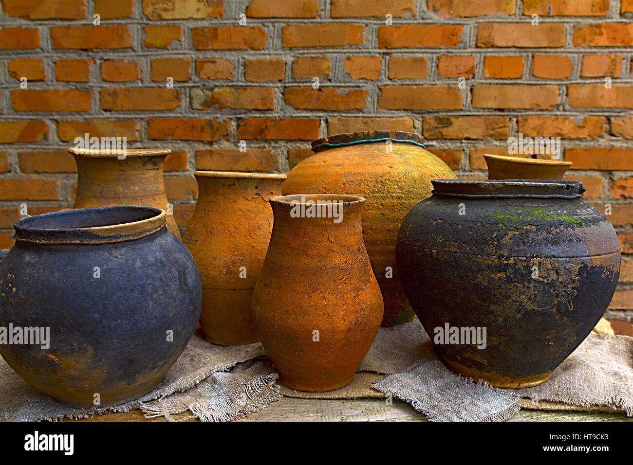 Des pots en argile de poterie, debout sur une table en bois sur un arrière-plan d'un mur de briques Banque D'Images