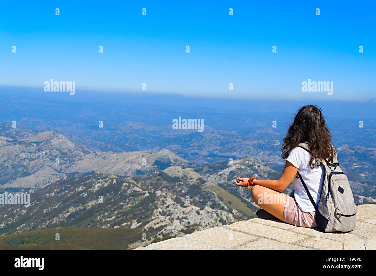 Fille assise sur le mont Lovcen au Monténégro dans les nuages et regarder le panorama des montagnes Banque D'Images