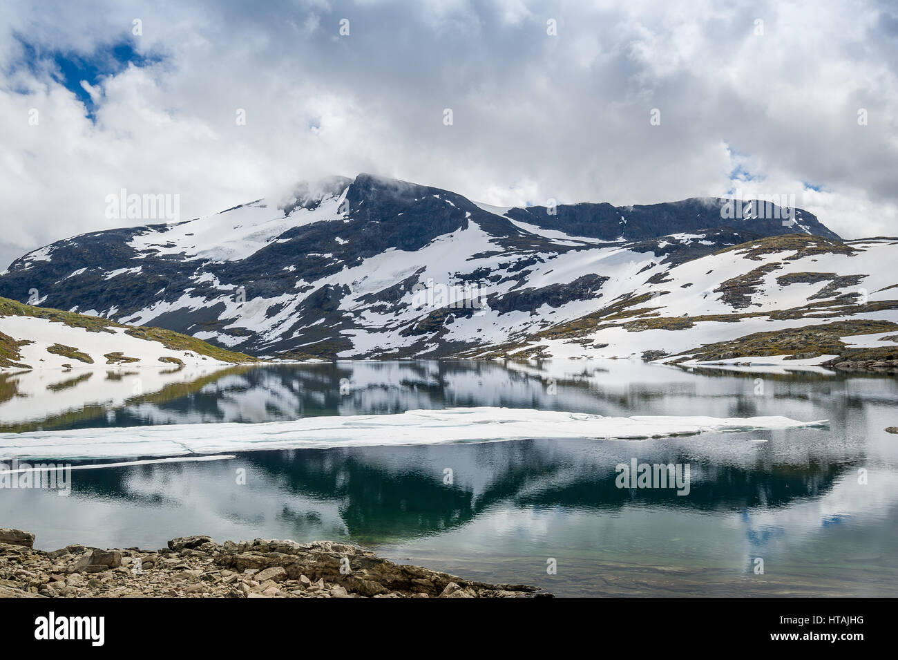 Paysage de montagne avec des rochers enneigés et de glace fondue lac avec belle réflexion. Road 55, route touristique nationale, la Norvège. Banque D'Images