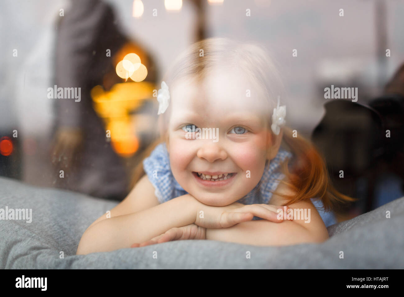 Cute little girl looking through window Banque D'Images