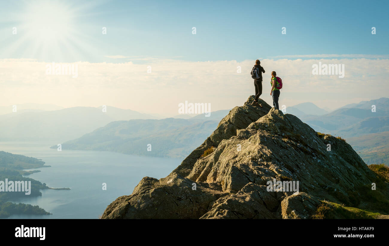 Deux randonneurs au sommet de la montagne bénéficiant d'une vue sur la vallée, ben, Loch Katrine, highlands, Scotland, UK Banque D'Images