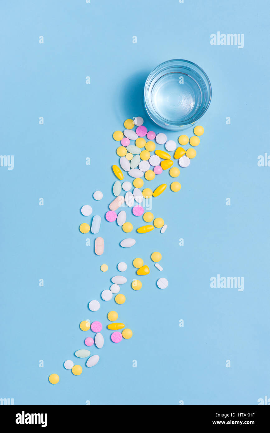 Pilules colorées avec de l'eau sur fond bleu. Banque D'Images