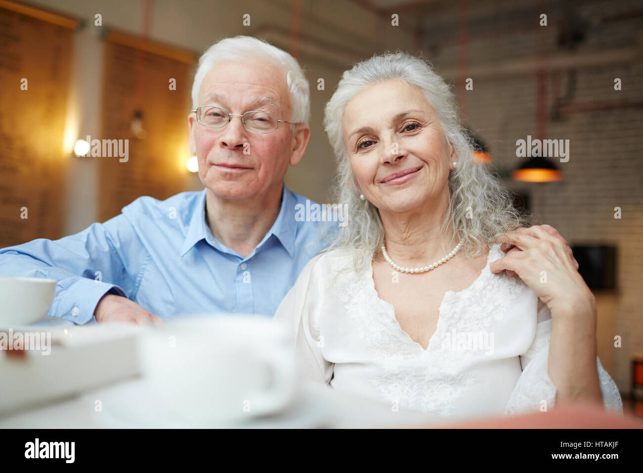 Consacrée senior couple looking at camera in cafe Banque D'Images