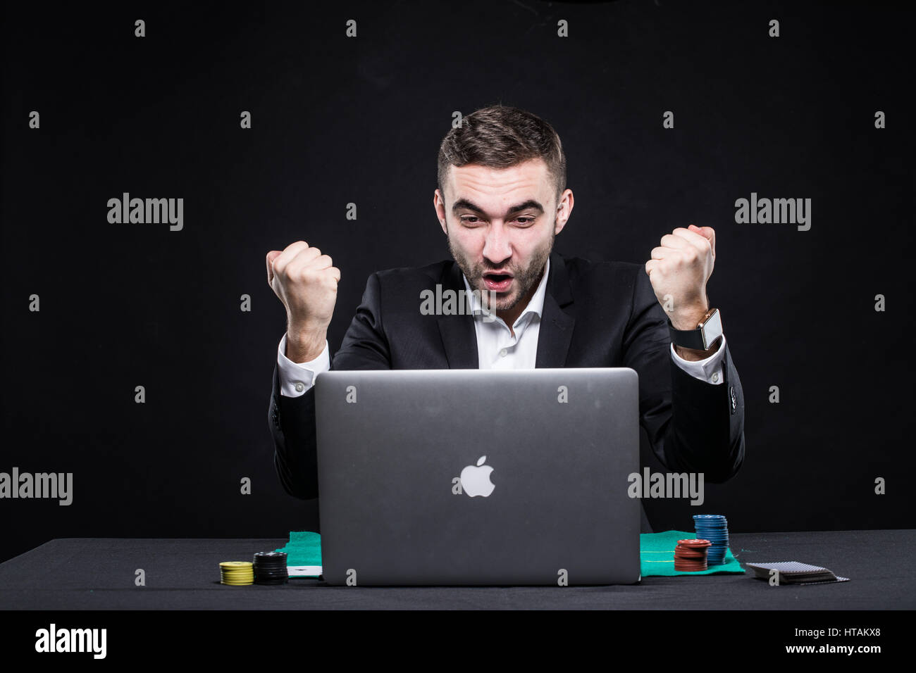 Le poker en ligne joueur assis à la table avec ordinateur portable et des jetons de poker sur fond noir Banque D'Images