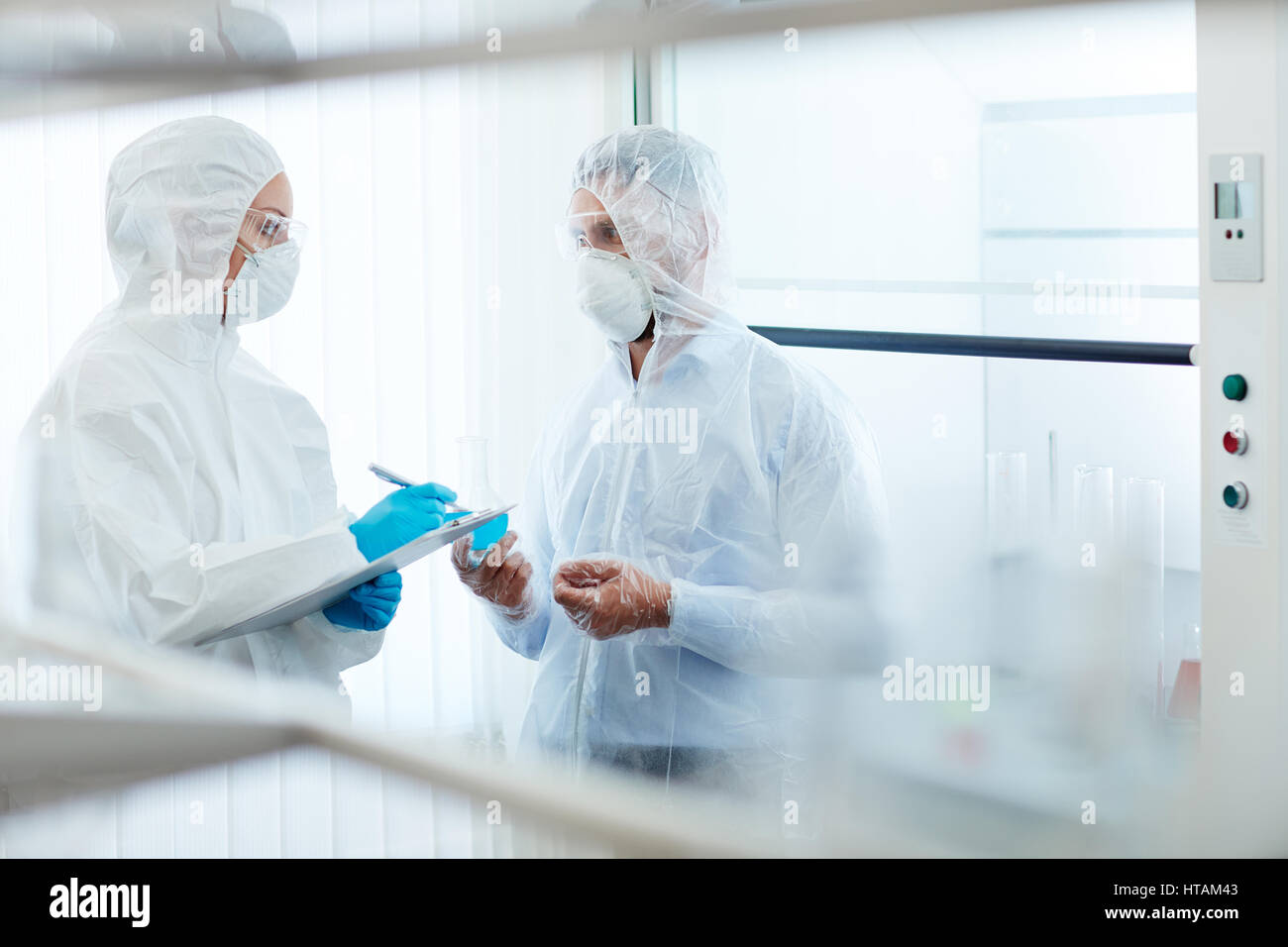 Deux scientifiques contemporains en uniforme de protection travaillant en laboratoire chimique Banque D'Images
