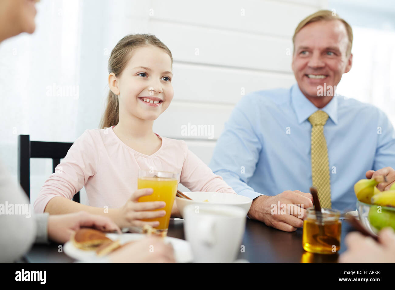 Jeune fille souriante et son père assis par table en petit déjeuner Banque D'Images
