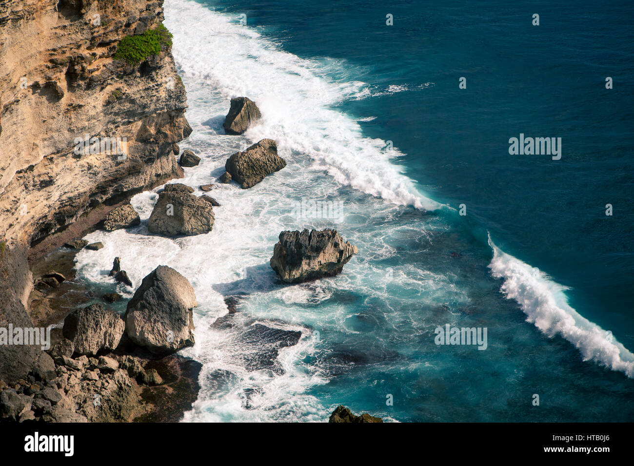 Les vagues de l'océan sur l'écrasement d'énormes rochers sur la plage par une journée ensoleillée. Bali Indonésie Banque D'Images