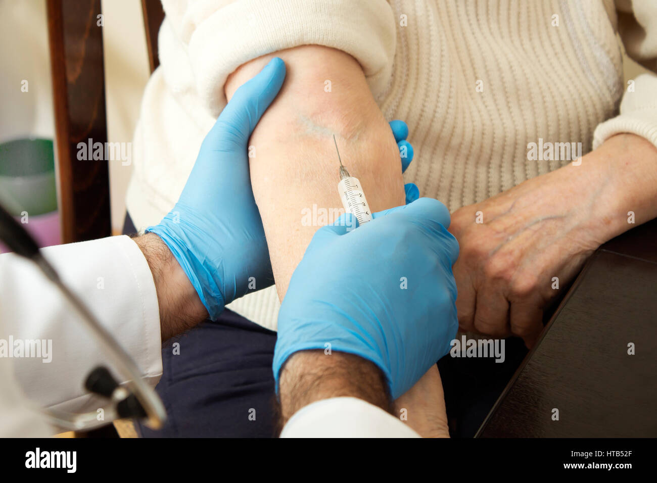 Le médecin met une aiguille dans la veine de la vieille femme. Médecin mains porter des gants lors de l'administration de l'injection au patient. Banque D'Images