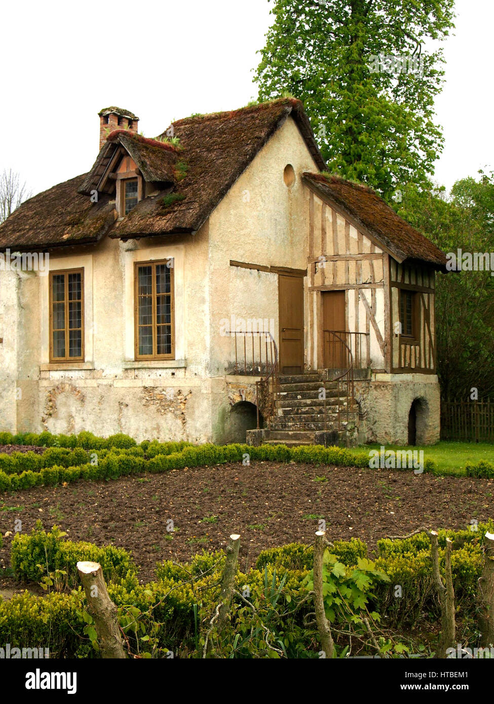 Un cottage traditionnel français avec un petit jardin et d'un toit de chaume. Banque D'Images