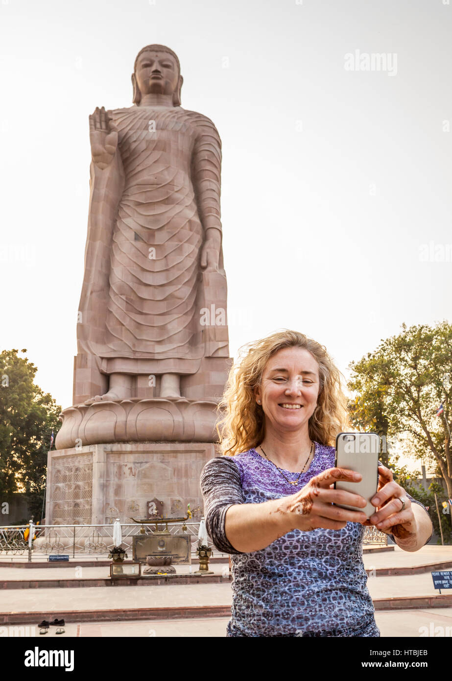 Une femme prenant un autoportrait d'elle-même en face de Bouddha Thai Vihar à Sarnath, l'Inde. Banque D'Images