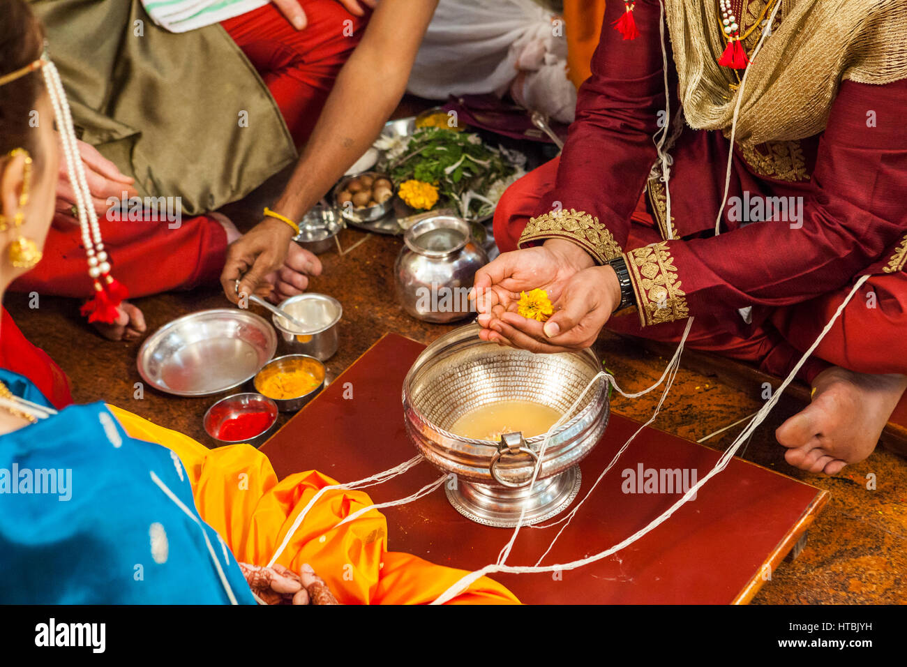 Le marié à un mariage hindou / indienne tient une fleur au-dessus d'un bol en argent. Banque D'Images