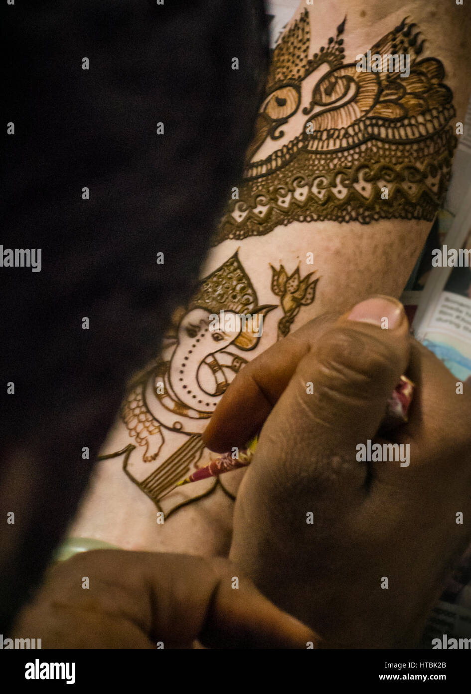 Une Henna Mehndi / artiste travaillant sur un bras de la mariée henné lors d'une partie. La figure de l'éléphant Ganesha, est l'un des plus connu et le plus vénéré dieti Banque D'Images