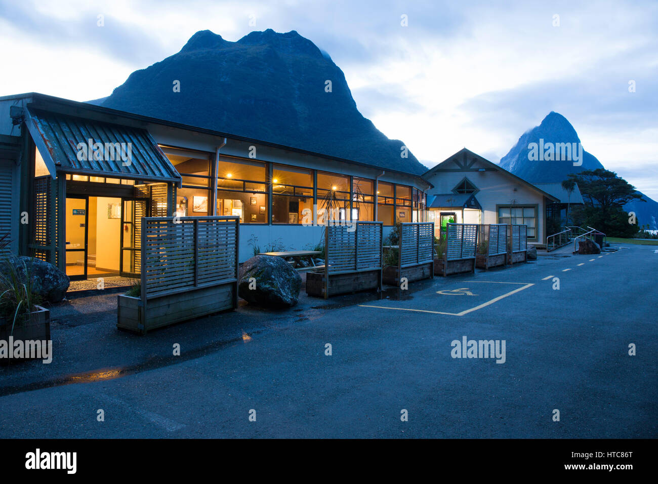Milford Sound, Fiordland National Park, Southland, Nouvelle-Zélande. Le Café Canard bleu allumé à la tombée de la Mitre Peak, visible dans l'arrière-plan. Banque D'Images