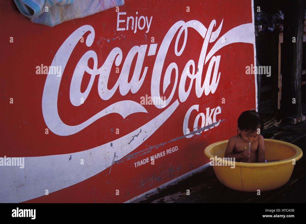 La pauvreté : faire des bulles en face de Coca-Cola minable enseigne publicitaire. Le tiers monde est conforme à la première. Girl meets World. Banque D'Images La pauvreté : faire des bulles en face de Coca-Cola minable enseigne publicitaire. Le tiers monde est conforme à la première. Girl meets World. Banque D'Images