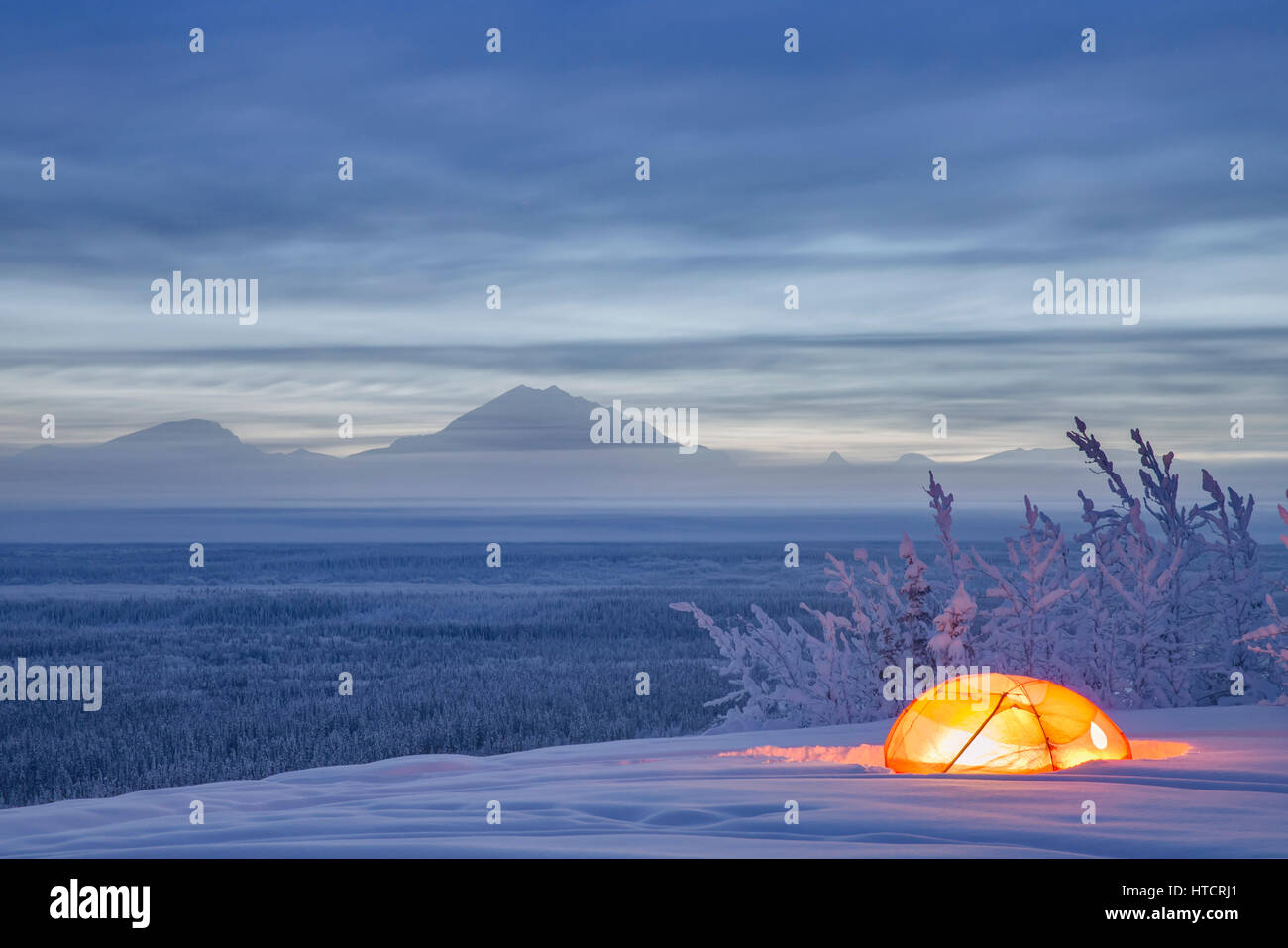 Le mont enneigé et le tambour de la vallée de la rivière de cuivre au crépuscule avec une tente éclairée de l'intérieur de l'avant-plan, Southcentral Alaska, USA, Hiver Banque D'Images