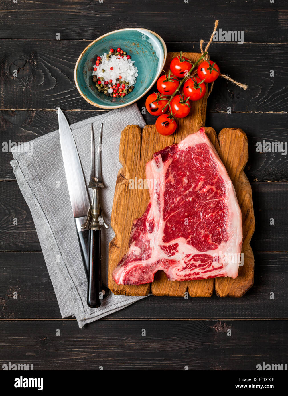 La viande fraîche de matières premières, de l'expérience et du steak Club fourchette et couteau de viande sur fond de bois sombre, vue du dessus Banque D'Images