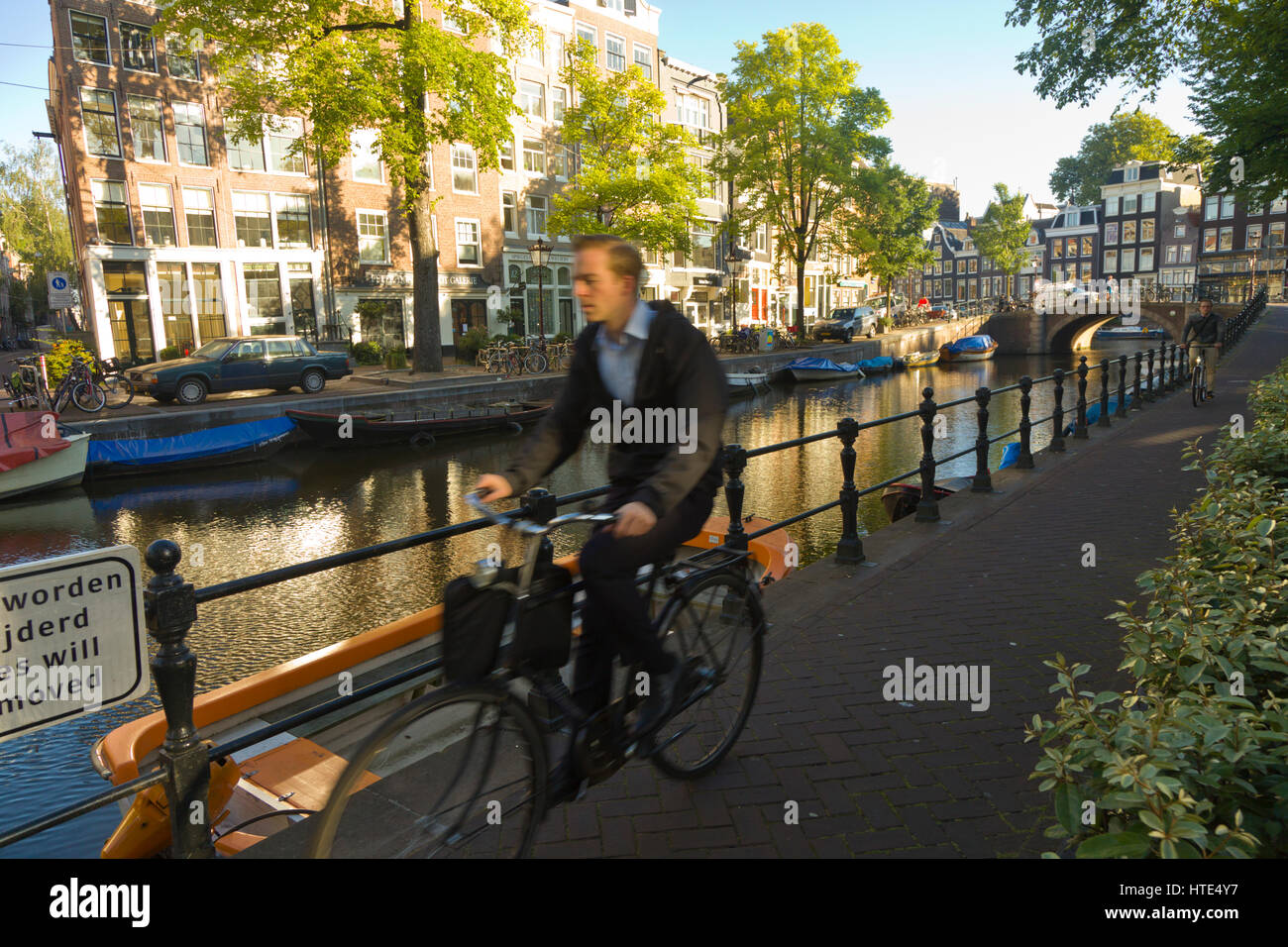 À vélo au travail le long d'un canal d'Amsterdam, chemins de remorquage sur un matin ensoleillé Banque D'Images