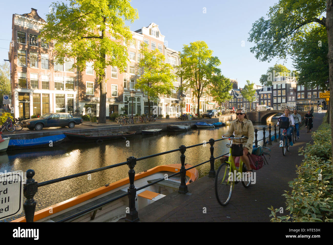 À vélo au travail le long d'un canal d'Amsterdam, chemins de remorquage sur un matin ensoleillé Banque D'Images