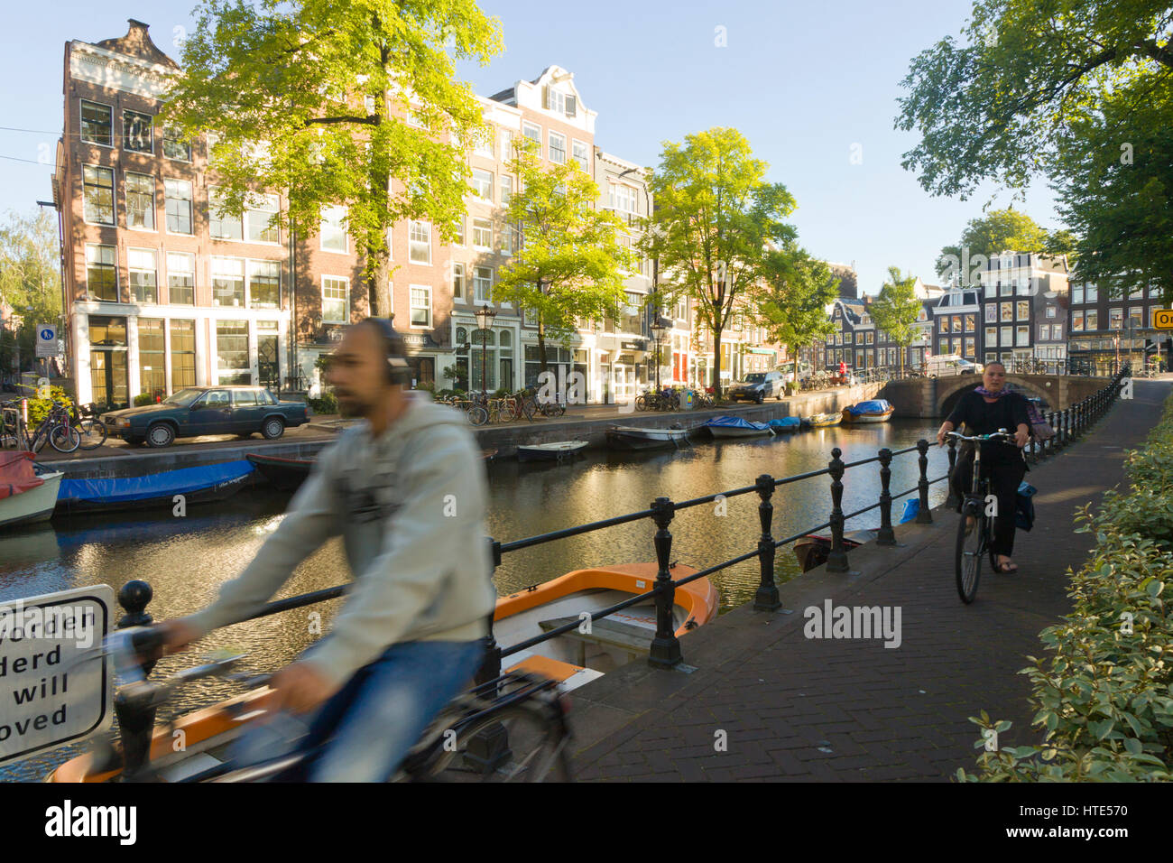 À vélo au travail le long d'un canal d'Amsterdam, chemins de remorquage sur un matin ensoleillé Banque D'Images
