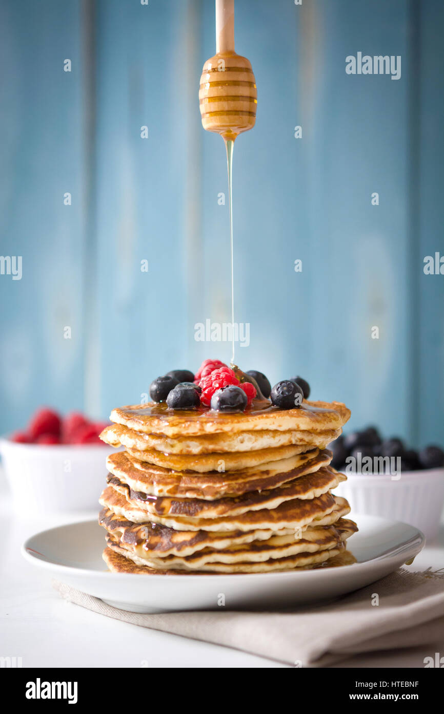 Verser le miel miel cuillère sur pancake Banque D'Images