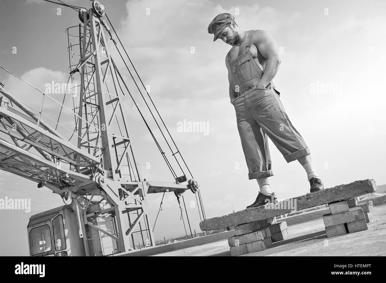 Le temps de réfléchir. Low angle shot monochrome d'une jeune homme musclé builder habillé en vêtements vintage debout sur le toit d'un bâtiment les peo Banque D'Images