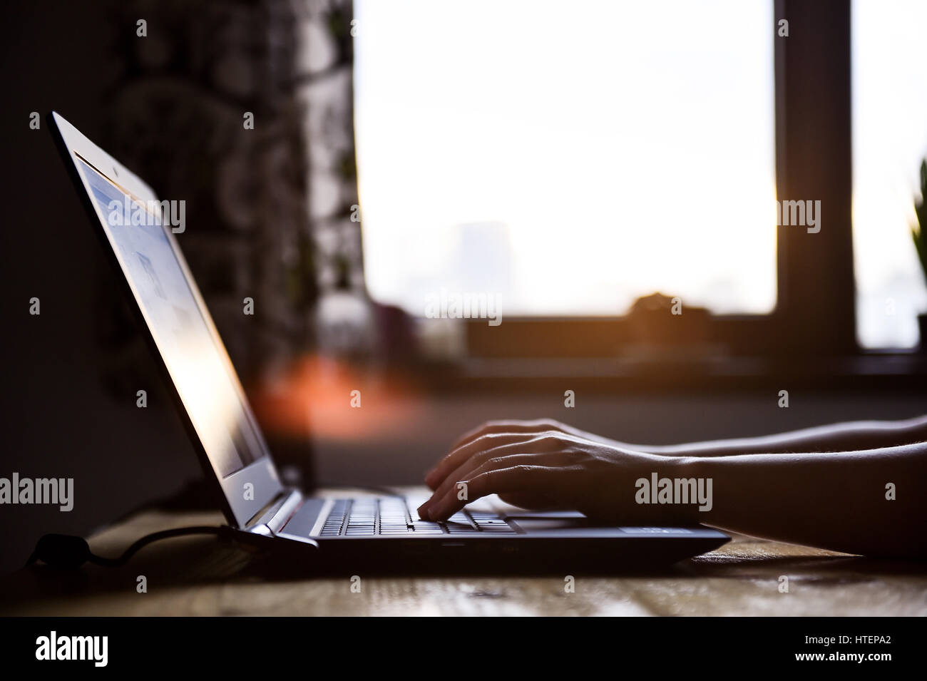Femme à l'intérieur de la main d'un ordinateur portable avec beau coucher du soleil la lumière en arrière-plan Banque D'Images