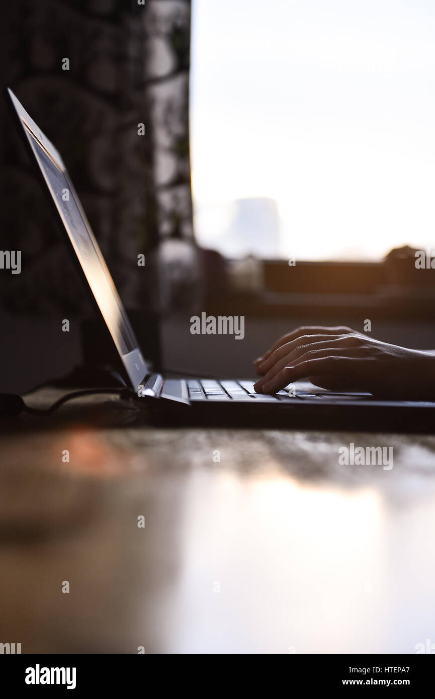 Femme à l'intérieur de la main d'un ordinateur portable avec beau coucher du soleil la lumière en arrière-plan Banque D'Images