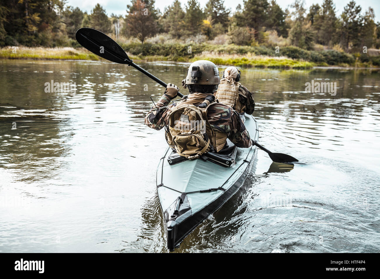 Les hommes des forces spéciales avec des visages peints en tenue de camouflage de l'armée de pagaie en kayak. Bateau de l'autre côté de la rivière, la mission de diversion, vue arrière Banque D'Images Les hommes des forces spéciales avec des visages peints en tenue de camouflage de l'armée de pagaie en kayak. Bateau de l'autre côté de la rivière, la mission de diversion, vue arrière Banque D'Images