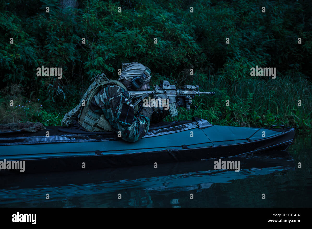 L'homme des forces spéciales avec visage peint en camouflage armée en kayak. La recherche d'objectif, mission de diversion, crépuscule Banque D'Images L'homme des forces spéciales avec visage peint en camouflage armée en kayak. La recherche d'objectif, mission de diversion, crépuscule Banque D'Images