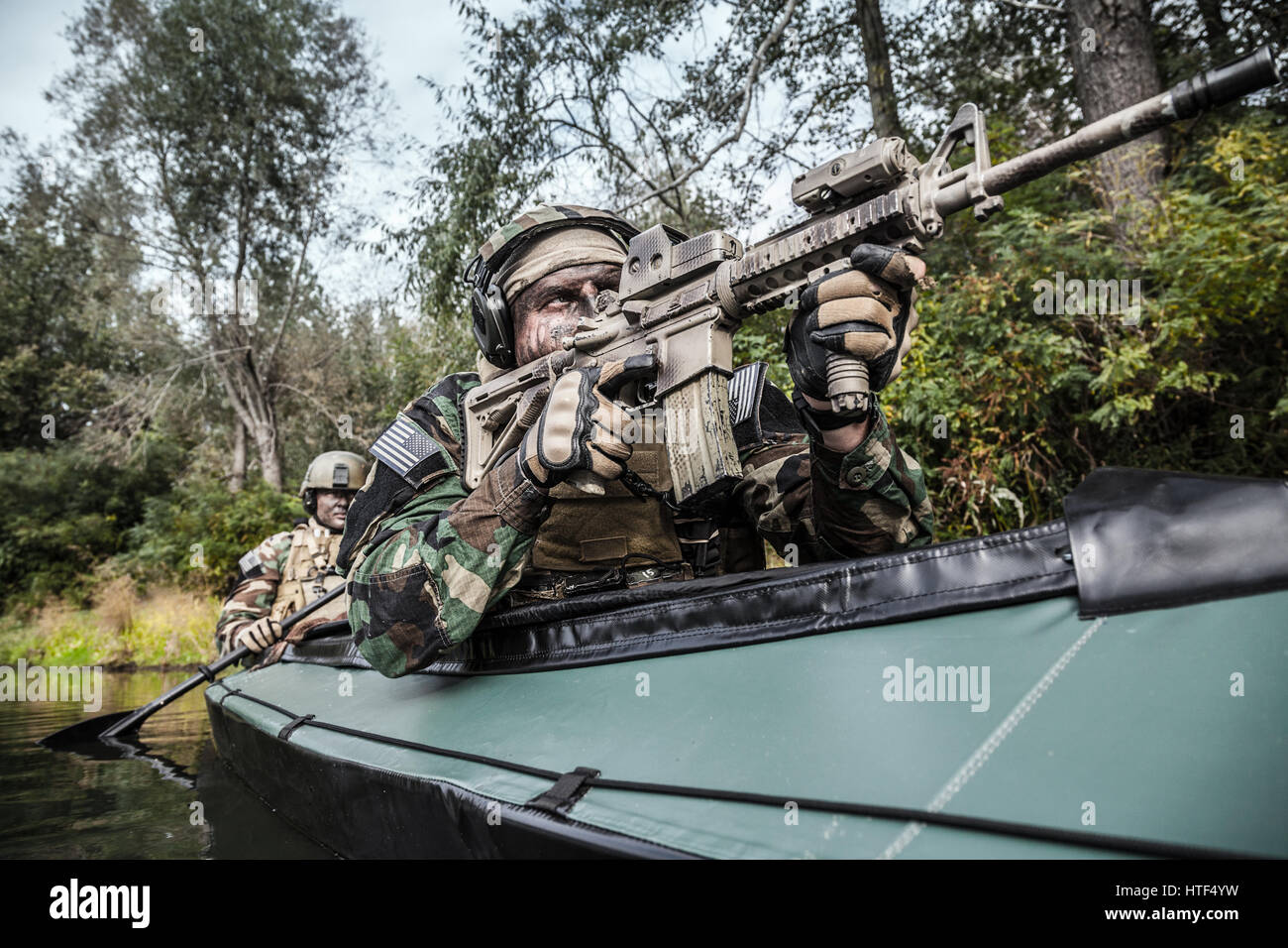 Les hommes des forces spéciales avec des visages peints en tenue de camouflage de l'armée de pagaie en kayak. Bateau de l'autre côté de la rivière, la mission de diversion, avant petit voir Banque D'Images Les hommes des forces spéciales avec des visages peints en tenue de camouflage de l'armée de pagaie en kayak. Bateau de l'autre côté de la rivière, la mission de diversion, avant petit voir Banque D'Images