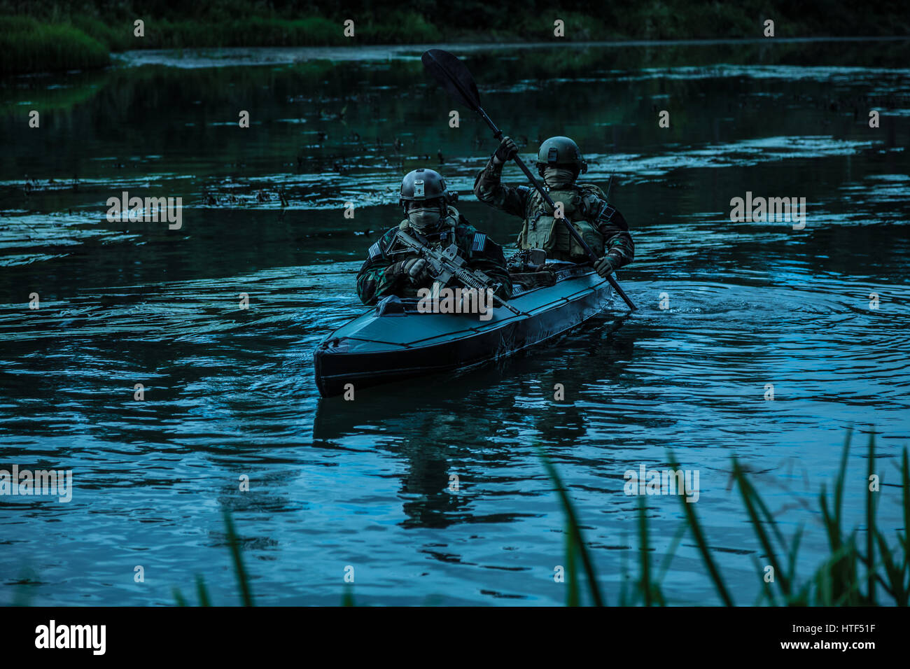 Les hommes des forces spéciales avec des visages peints en tenue de camouflage de l'armée de pagaie en kayak. Bateau calmement de l'autre côté de la rivière, la mission de diversion, crépuscule Banque D'Images Les hommes des forces spéciales avec des visages peints en tenue de camouflage de l'armée de pagaie en kayak. Bateau calmement de l'autre côté de la rivière, la mission de diversion, crépuscule Banque D'Images