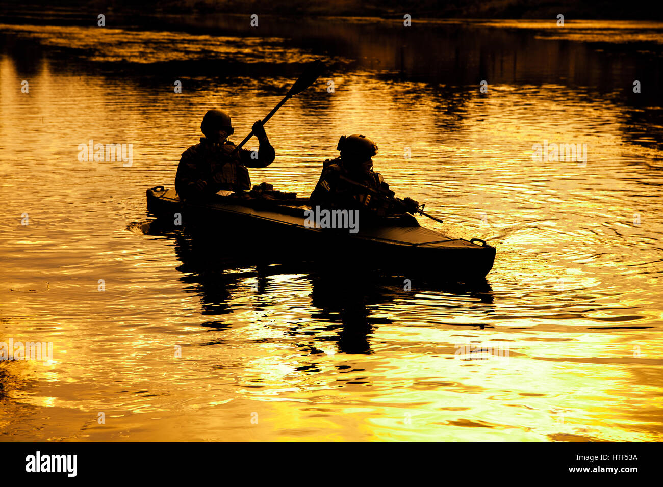 Silhouette d'hommes des forces spéciales de l'armée de pagaie en kayak. Bateau calmement de l'autre côté de la rivière, la mission de diversion, coucher de soleil Banque D'Images Silhouette d'hommes des forces spéciales de l'armée de pagaie en kayak. Bateau calmement de l'autre côté de la rivière, la mission de diversion, coucher de soleil Banque D'Images