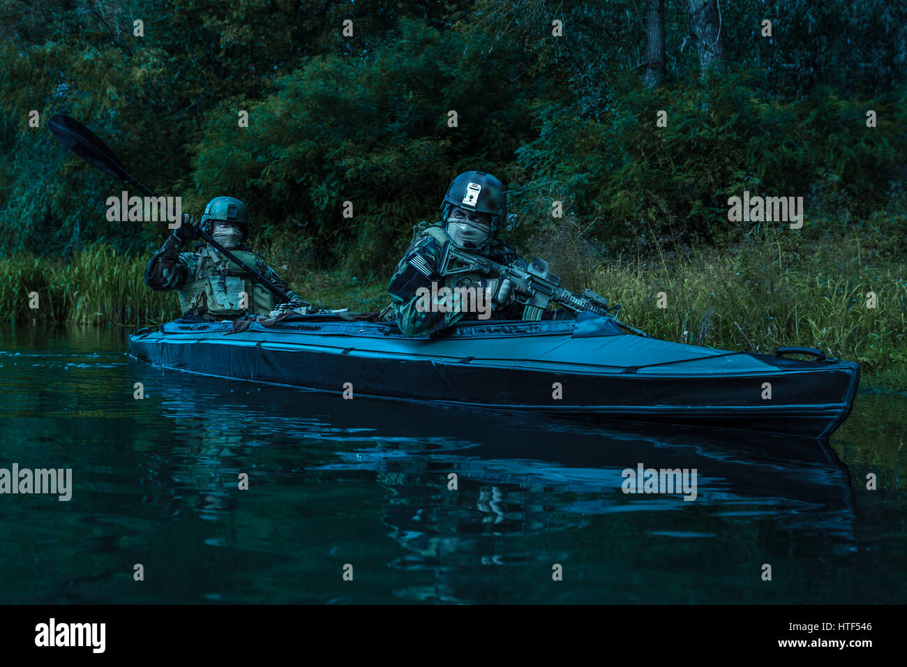 Les hommes des forces spéciales avec des visages peints en tenue de camouflage de l'armée de pagaie en kayak. Bateau calmement de l'autre côté de la rivière, la mission de diversion, crépuscule Banque D'Images Les hommes des forces spéciales avec des visages peints en tenue de camouflage de l'armée de pagaie en kayak. Bateau calmement de l'autre côté de la rivière, la mission de diversion, crépuscule Banque D'Images