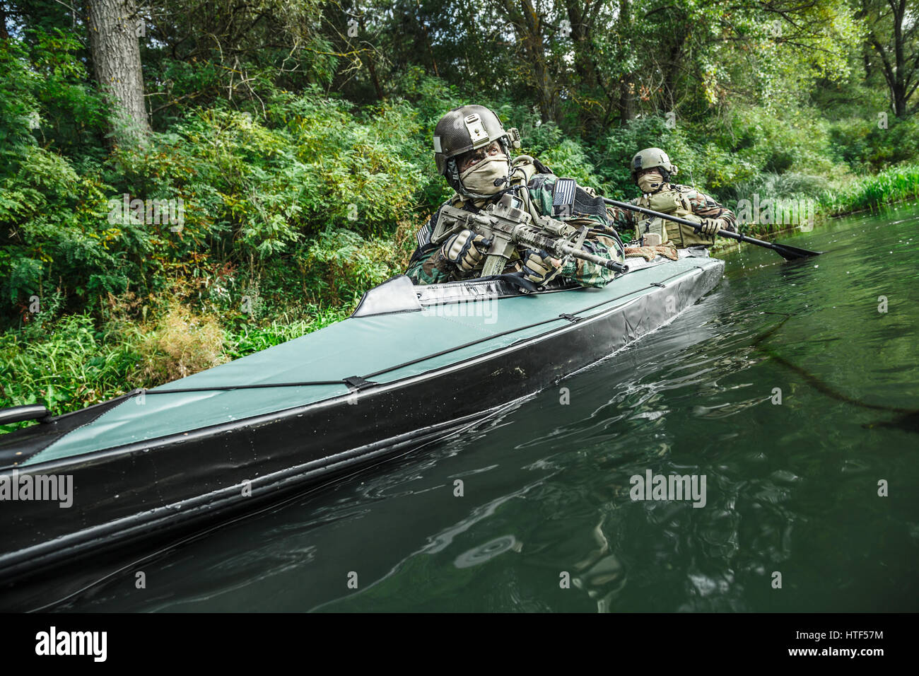 Les hommes des forces spéciales avec des visages peints en tenue de camouflage de l'armée de pagaie en kayak. Déménagement en bateau sur la rivière, vue sur la diagonale, la mission de diversion Banque D'Images Les hommes des forces spéciales avec des visages peints en tenue de camouflage de l'armée de pagaie en kayak. Déménagement en bateau sur la rivière, vue sur la diagonale, la mission de diversion Banque D'Images