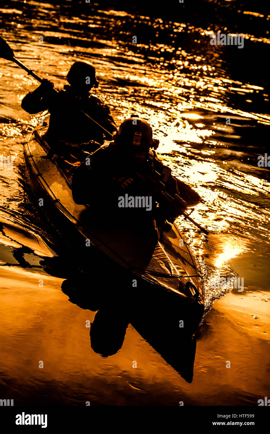 Silhouette d'hommes des forces spéciales de l'armée de pagaie en kayak. Bateau calmement de l'autre côté de la rivière, la mission de diversion, coucher de soleil Banque D'Images Silhouette d'hommes des forces spéciales de l'armée de pagaie en kayak. Bateau calmement de l'autre côté de la rivière, la mission de diversion, coucher de soleil Banque D'Images
