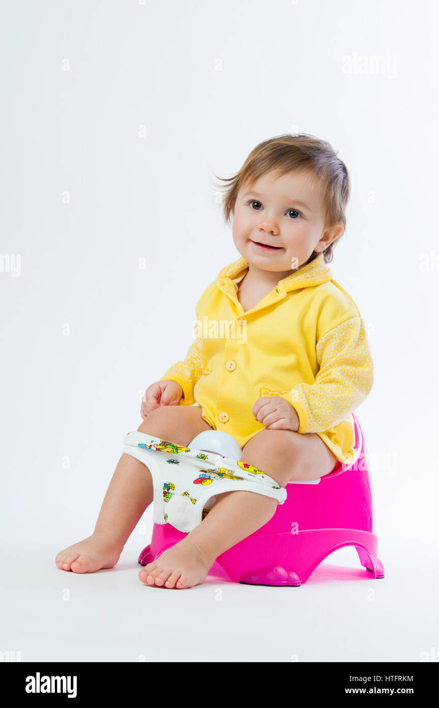 Little smiling girl sitting on un pot. Isolé sur fond blanc Banque D'Images