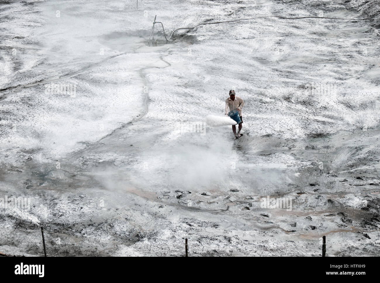 Asian farmer répandre de la poudre de chaux, antiseptique pour l'étang de la crevette, l'homme travaillant sur le lac séché, se préparer pour la nouvelle récolte de l'aquaculture, Delta du Mekong, Vietnam Banque D'Images