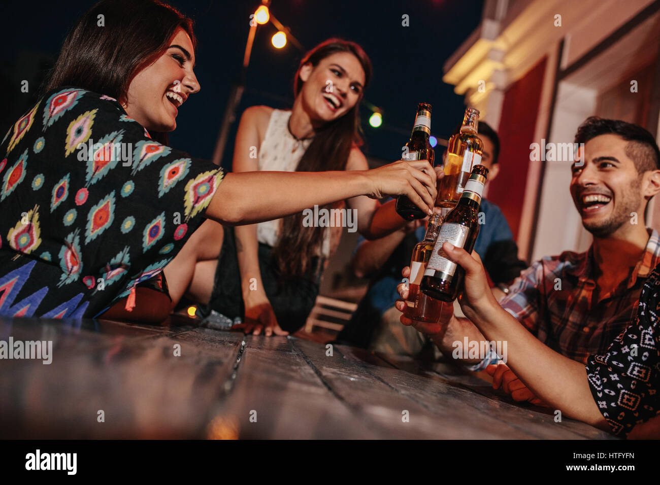 Groupe d'amis toasting drinks at a party en soirée. Les jeunes hanging out at rooftop party et profiter de boissons. Banque D'Images